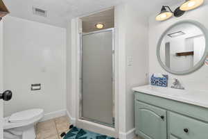 Bathroom with tile patterned flooring, vanity, toilet, and a shower with door