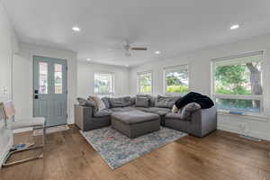 Living room featuring ceiling fan, dark hardwood / wood-style floors, ornamental molding, and a wealth of natural light