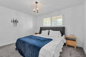 Bedroom featuring carpet, ornamental molding, and a notable chandelier