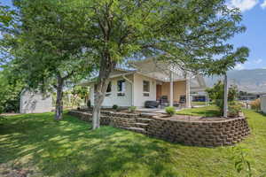 Back of house featuring a lawn, a mountain view, a pergola, and a patio