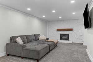 Carpeted living room with a fireplace and crown molding