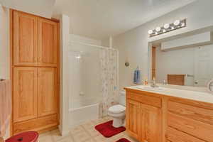 Full bathroom with vanity, toilet, a textured ceiling, and shower / tub combo