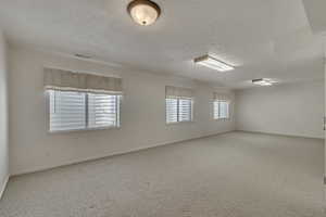 Spare room with a textured ceiling, carpet flooring, baseboards, and visible vents