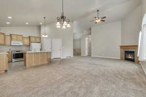 Kitchen with open floor plan, light carpet, ceiling fan, and white appliances
