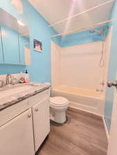 Full bathroom featuring vanity,  shower combination, toilet, and wood-type flooring