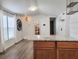 Kitchen featuring light hardwood / wood-style floors, light stone counters, and lofted ceiling