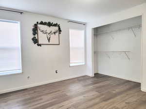 Unfurnished bedroom featuring hardwood / wood-style flooring, multiple windows, and a closet