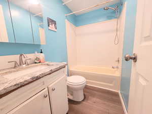 Full bathroom featuring hardwood / wood-style flooring, vanity, toilet, and shower / bathing tub combination