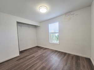 Unfurnished bedroom featuring dark hardwood / wood-style flooring and a closet