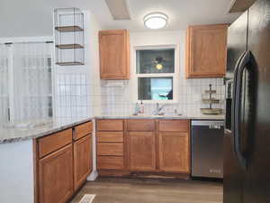 Kitchen featuring dishwasher, sink, black refrigerator with ice dispenser, dark hardwood / wood-style flooring, and light stone counters