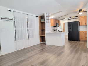 Kitchen with kitchen peninsula, backsplash, ceiling fan, and black appliances