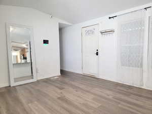 Entrance foyer featuring wood-type flooring and lofted ceiling