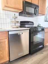 Kitchen featuring backsplash, black appliances, and light hardwood / wood-style floors