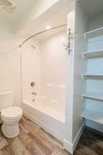 Bathroom featuring toilet, wood-type flooring, and washtub / shower combination