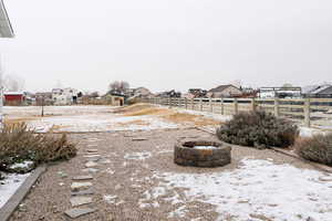 Yard layered in snow featuring a fire pit