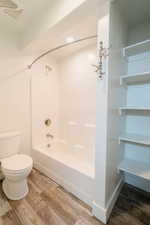 Bathroom featuring hardwood / wood-style floors, shower / bathtub combination, and toilet