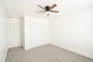 Unfurnished bedroom featuring ceiling fan, light carpet, and a closet