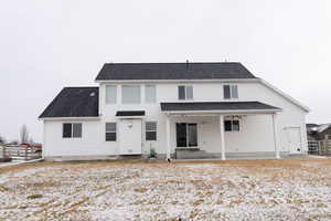 Snow covered back of property with a patio