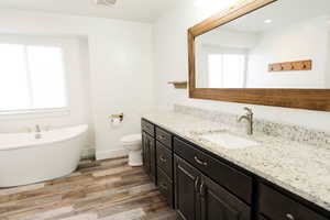 Bathroom featuring a wealth of natural light, hardwood / wood-style floors, vanity, and a bath