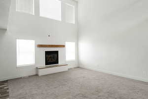 Unfurnished living room featuring carpet floors and a high ceiling