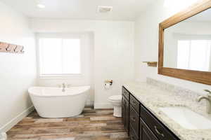 Bathroom featuring hardwood / wood-style floors, a washtub, a wealth of natural light, and vanity