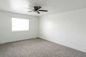 Carpeted spare room featuring ceiling fan