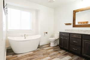 Bathroom featuring a bathing tub, vanity, toilet, and wood-type flooring