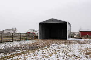 Snow covered structure featuring a carport