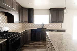 Kitchen with light stone countertops, sink, gas range oven, and dark brown cabinets