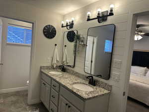 Bathroom with vanity, a textured ceiling, ceiling fan, toilet, and wood walls