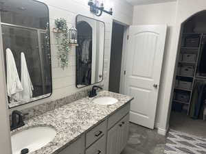 Bathroom featuring wooden walls, vanity, and a shower with shower door