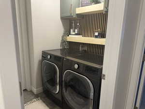 Clothes washing area with separate washer and dryer, light tile patterned floors, and cabinets