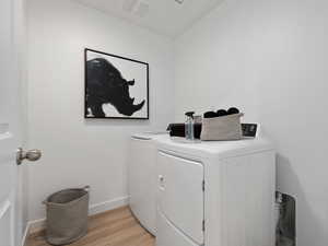 Laundry room with washer and dryer and light wood-type flooring