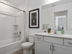 Full bathroom with shower / bath combo with shower curtain, vanity, hardwood / wood-style floors, and toilet