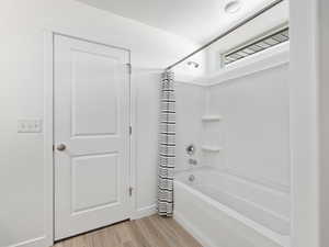 Bathroom with hardwood / wood-style floors and shower / bath combo with shower curtain