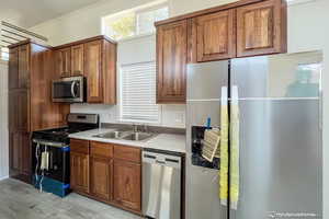 Kitchen featuring appliances with stainless steel finishes, light wood-type flooring, crown molding, and sink