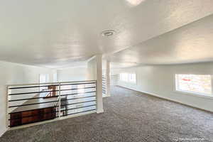 Bonus room featuring carpet flooring and a textured ceiling