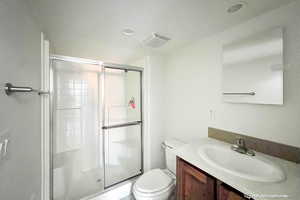 Bathroom with a shower with door, vanity, and toilet