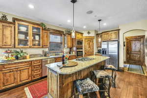 Kitchen featuring a large island, light granite countertops, stone wall and stainless steel appliances,