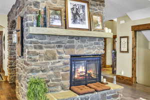 The living room features a triple-sided stone fireplace with a casual seating area or dining room beyond