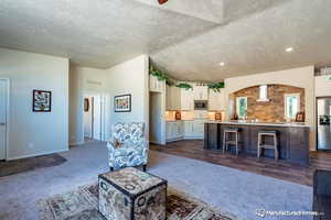 Unfurnished living room with dark colored carpet and a textured ceiling