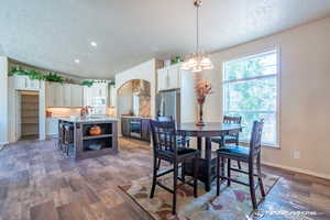 Dining space featuring a textured ceiling, dark wood-type flooring, sink, and a chandelier