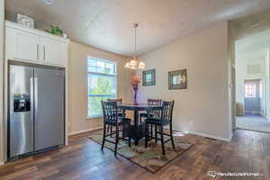 Dining area with dark hardwood / wood-style flooring, a textured ceiling, and a notable chandelier