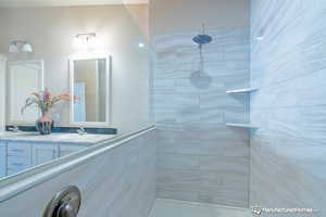 Bathroom featuring tiled shower and vanity