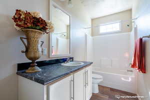 Full bathroom featuring hardwood / wood-style floors, vanity, washtub / shower combination, toilet, and a textured ceiling