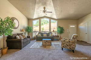 Living room with ceiling fan, carpet, and a textured ceiling