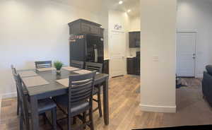 Dining room with baseboards, light wood-type flooring, and a towering ceiling