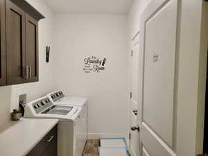 Laundry area with cabinets, separate washer and dryer, and light wood-type flooring