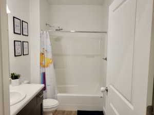 Full bathroom with shower / bath combo with shower curtain, vanity, hardwood / wood-style floors, and toilet