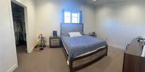 Bedroom featuring a spacious closet, baseboards, a closet, and light carpet